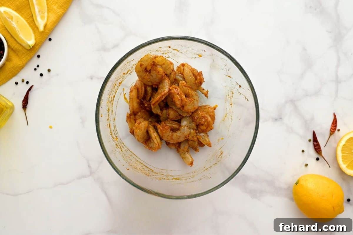 Raw shrimp being tossed in a bowl with a vibrant mixture of aromatic spices, a drizzle of olive oil, and fresh lemon zest, ensuring every piece is coated for maximum flavor.