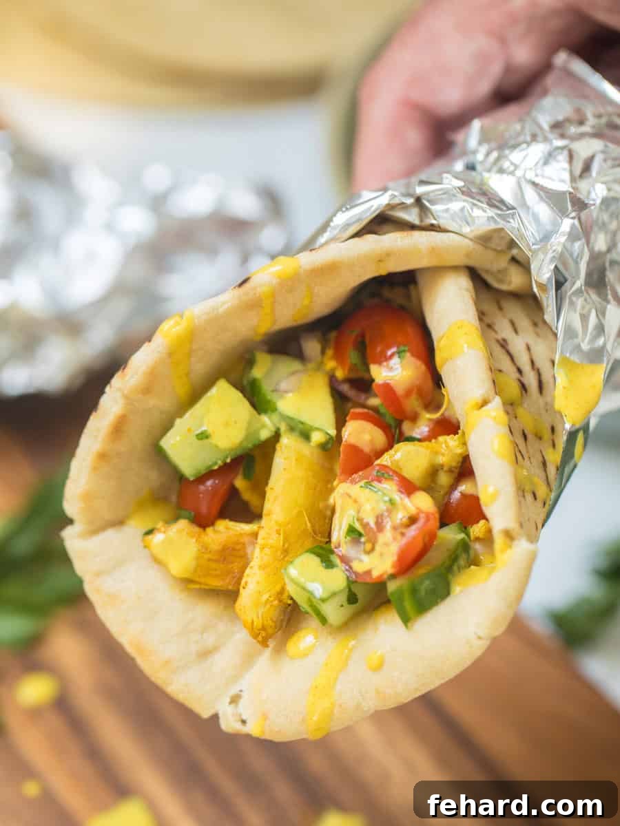 Delicious Chicken Shawarma served in warmed pita bread with fresh tomato cucumber topping and a generous drizzle of lemon tahini sauce.