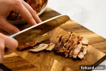 Grilled chicken shawarma on cutting board being cut into bite-sized pieces.