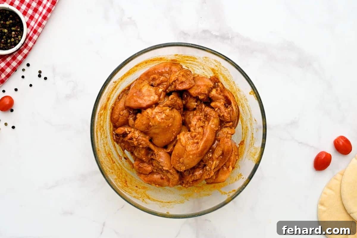 Boneless, skinless chicken thighs soaking in a rich, aromatic chicken shawarma marinade in a large mixing bowl, ready for cooking.