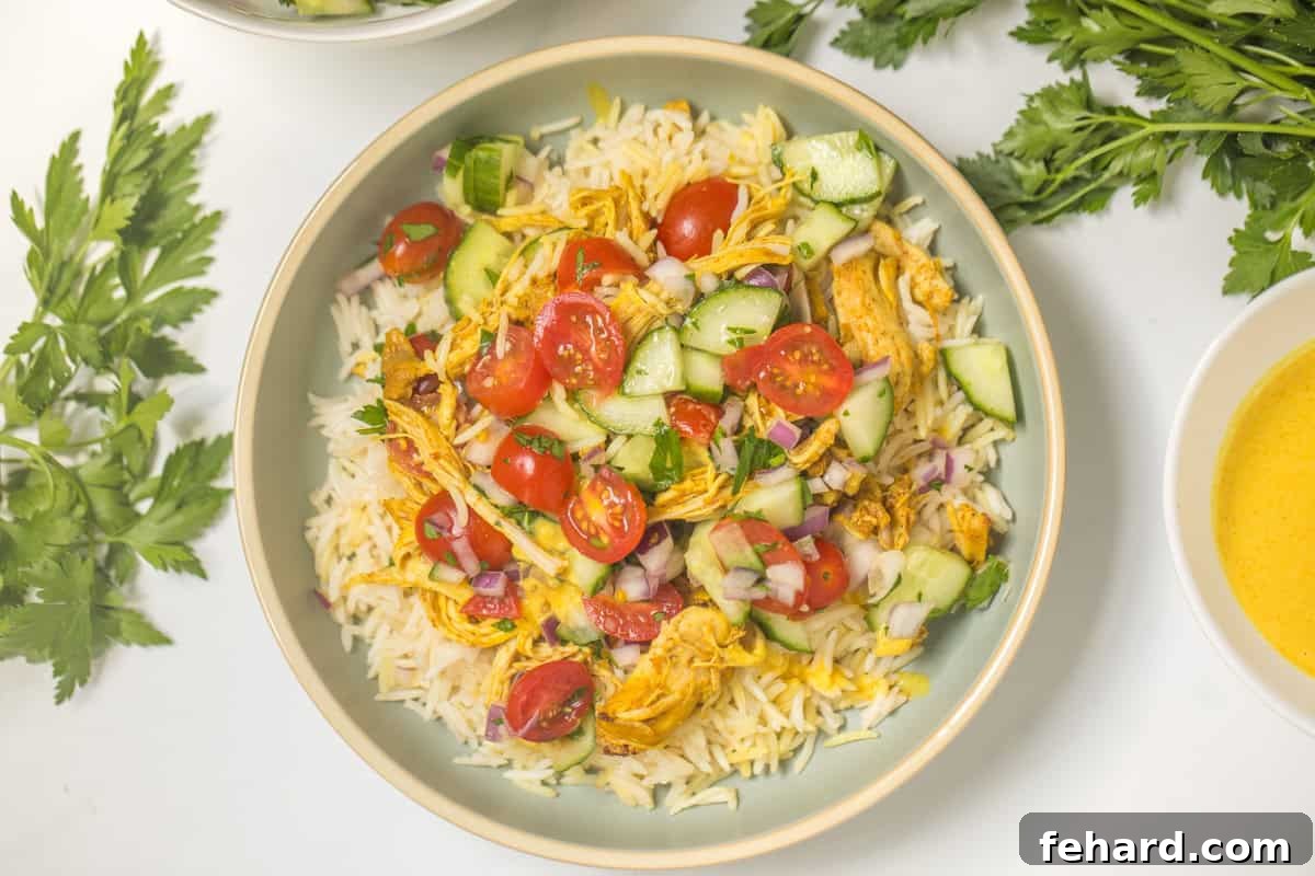 A vibrant Chicken Shawarma bowl featuring rice topped with diced chicken, a fresh cucumber tomato salad, and creamy lemon tahini sauce.