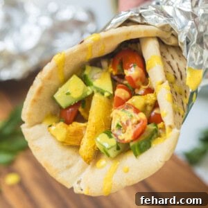 Chicken shawarma in warmed pita with tomato cucumber topping and lemon tahini sauce.