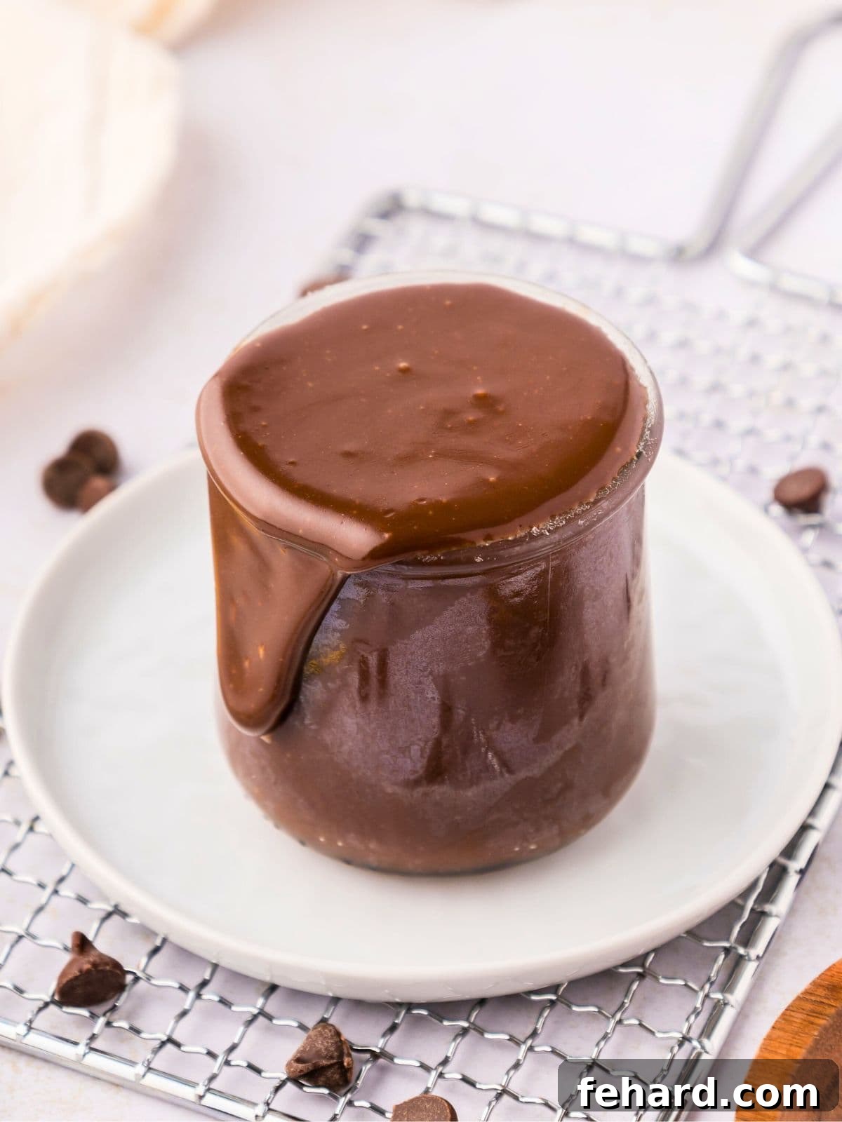Hot Fudge Recipe Homemade hot fudge sauce in a small jar next to chocolate chips and a sprinkle of sea salt.