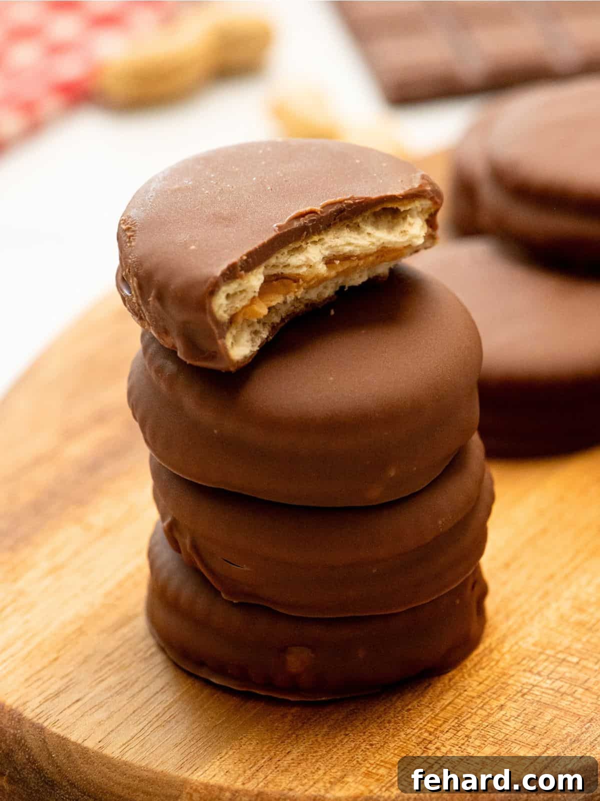 Homemade Tagalong Cookies stacked on top of each other with one broke open to show butter cracker, peanut butter, and chocolate layer.
