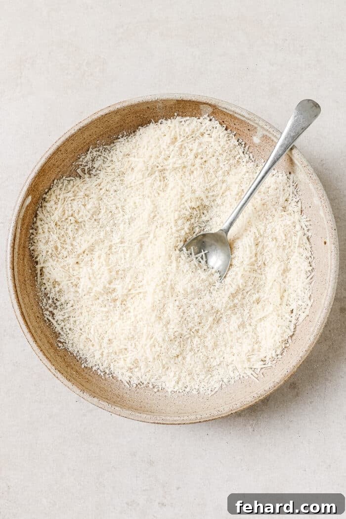 Breadcrumbs, parmesan cheese, and seasonings in a mixing bowl with a spoon in it.
