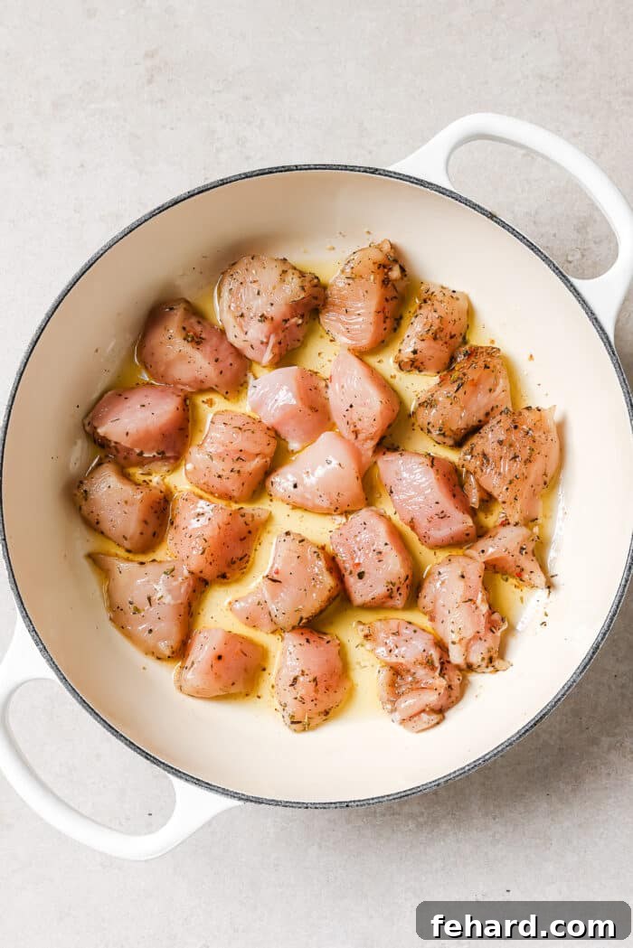 Raw seasoned chicken cooking in a single layer in a hot skillet