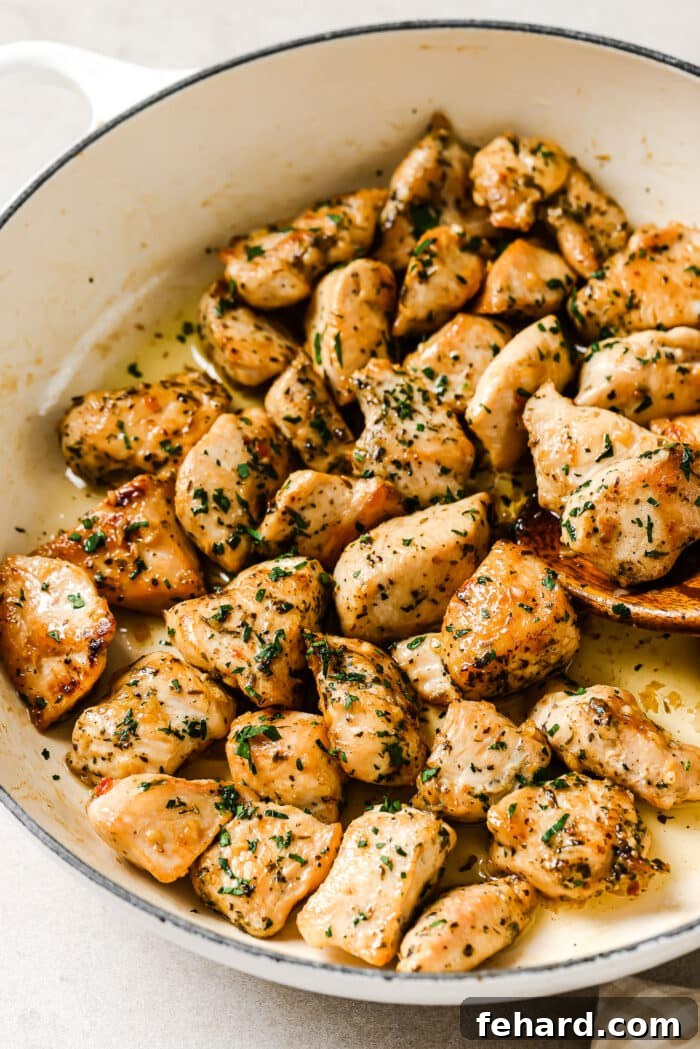 A closeup of glistening garlic butter chicken bites in a skillet, coated with fresh parsley.