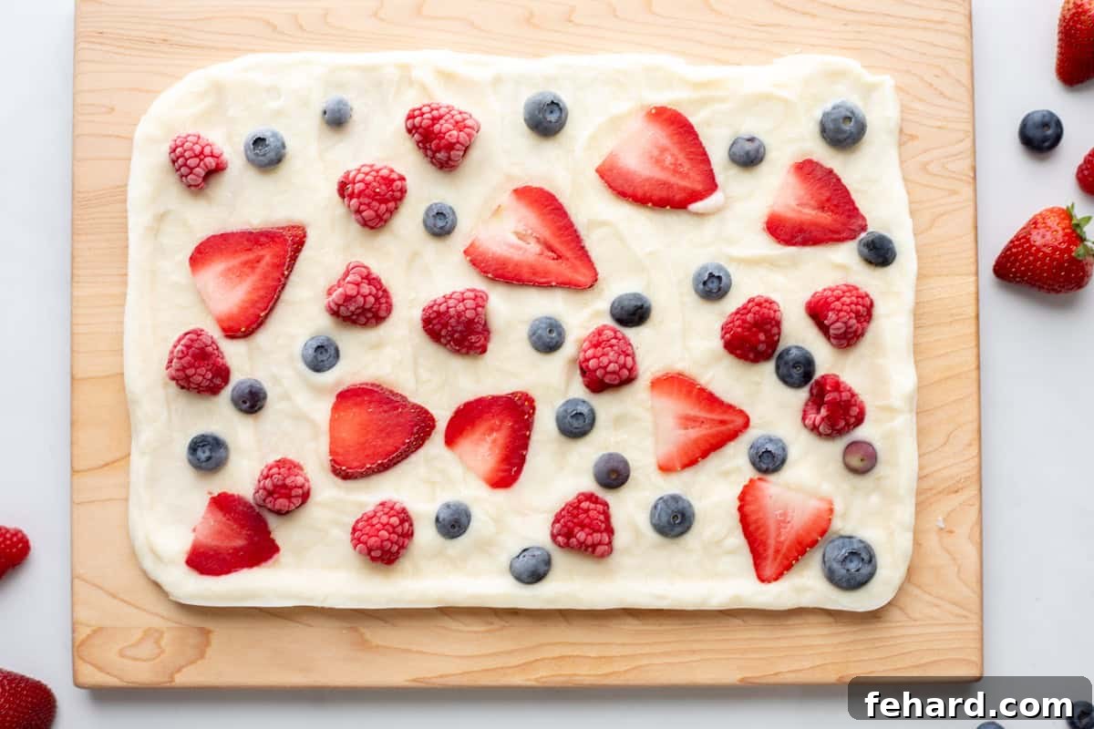 Healthy Frozen Yogurt Bark 3 Frozen Yogurt Bark with Berries on wooden cutting board with fresh berries on around the yogurt.