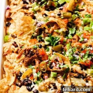 Rotisserie Chicken Nachos on a baking sheet with various toppings.