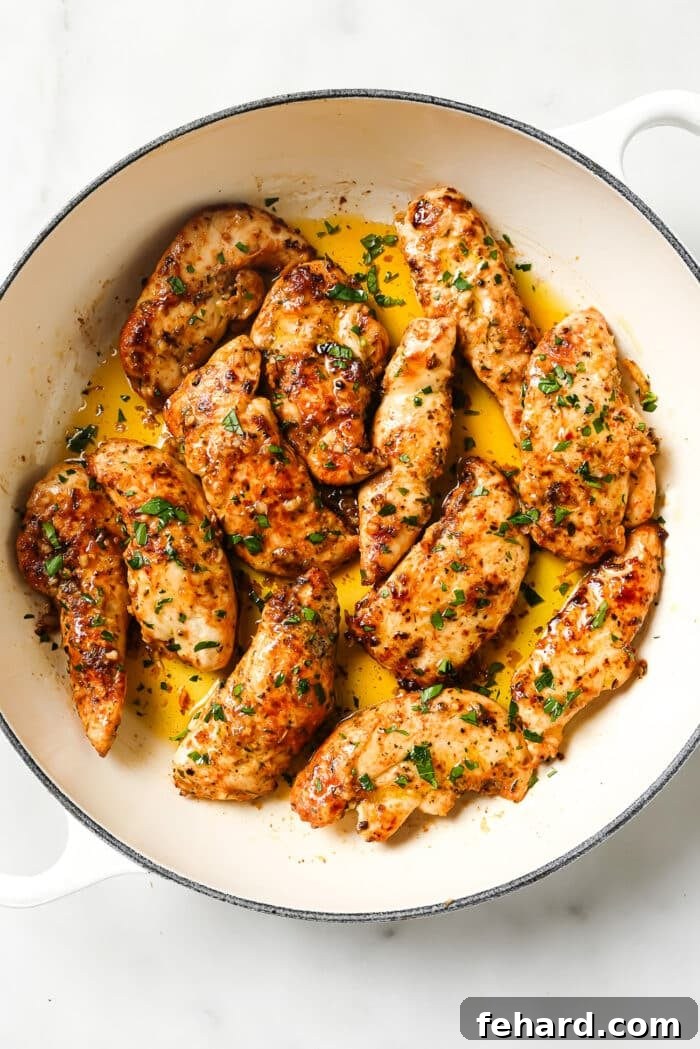 Garlic butter chicken tenders garnished with parsley in a ceramic cast-iron skillet. 