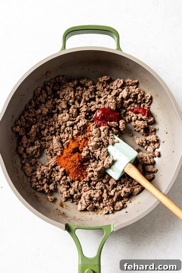 raw ground beef in a skillet with spices. 
