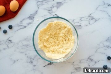 Close-up of butter mixed into flour and sugar until it forms a coarse, crumbly texture, ready for forming the shortbread base.
