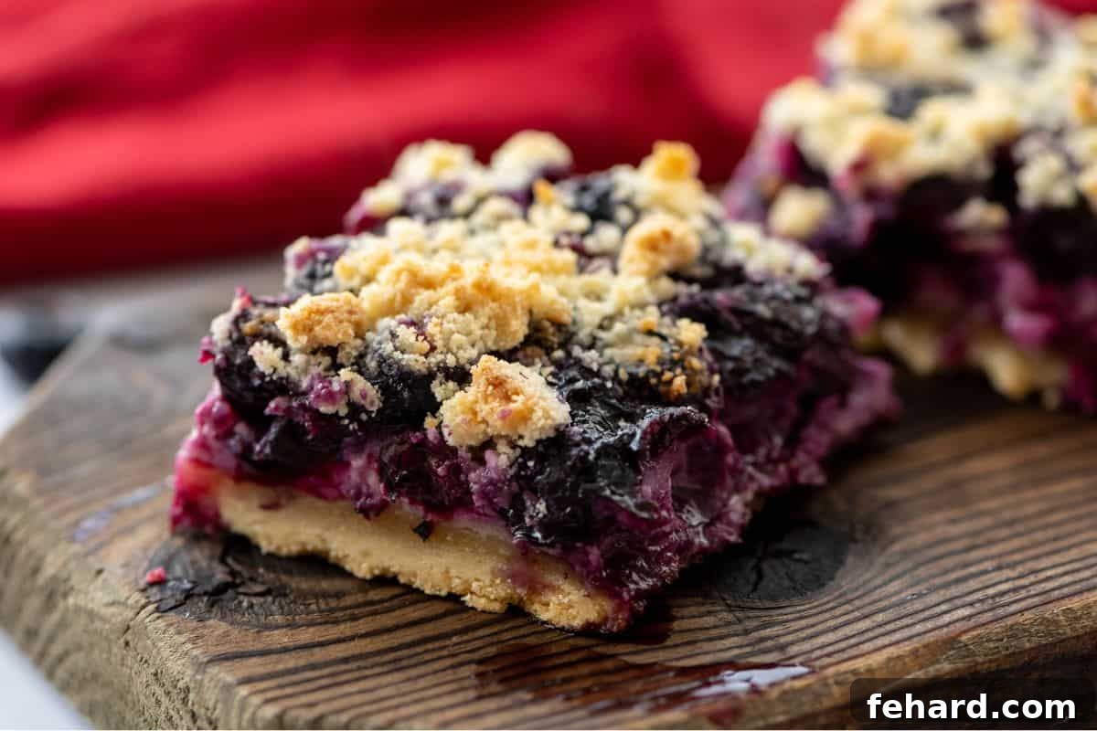 An inviting arrangement of perfectly sliced blueberry bars on a wooden cutting board, beautifully showcasing the golden shortbread crumble, vibrant blueberry filling, and crisp base.