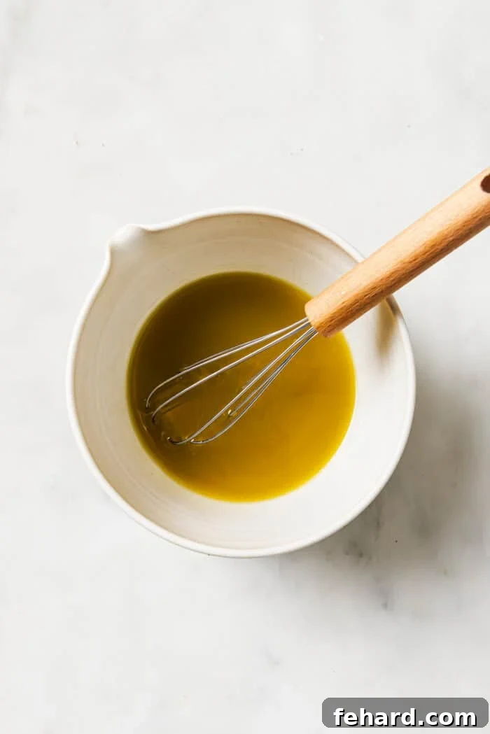 Homemade salad dressing in a white bowl with a whisk in it. 