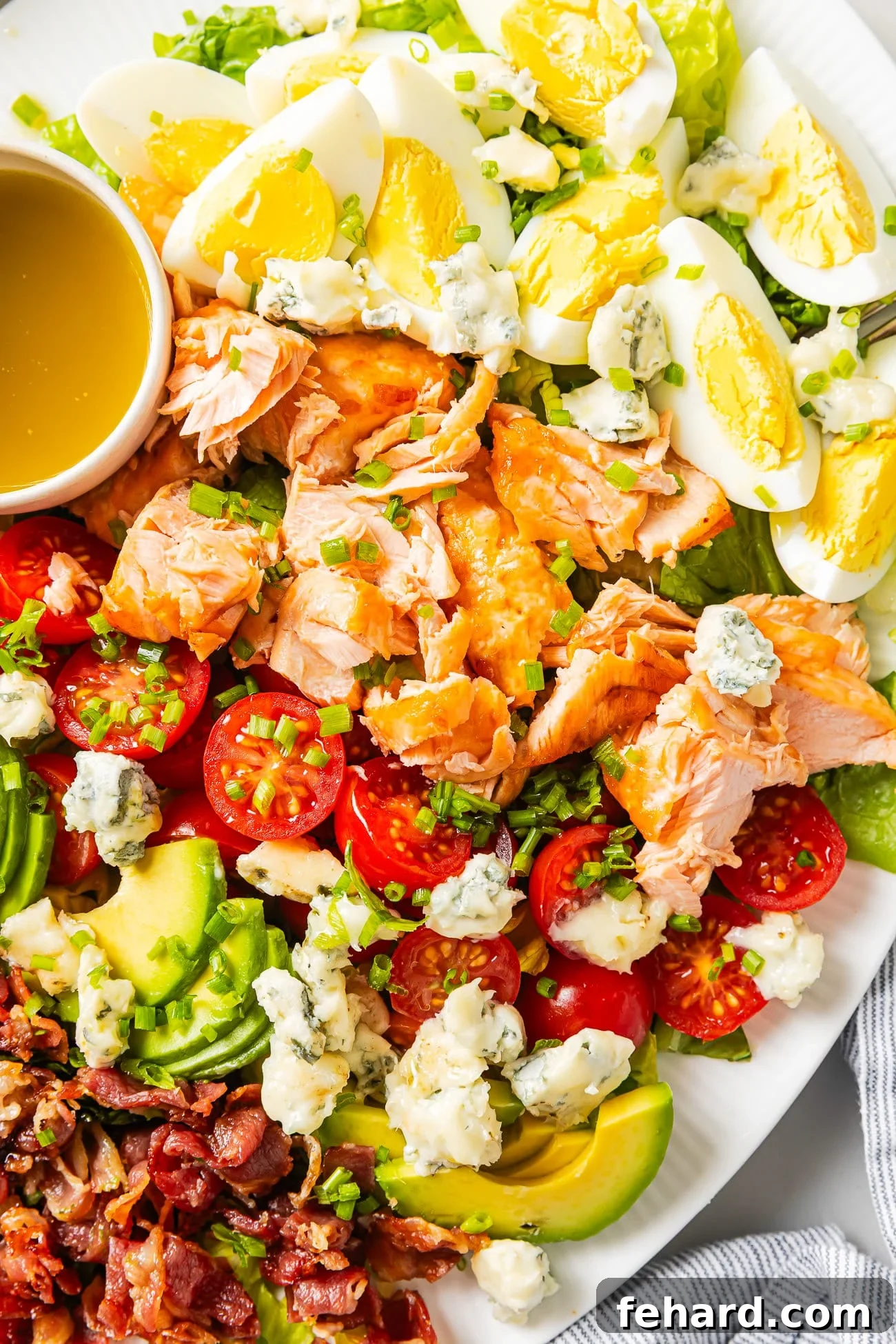 A closeup of a salmon cobb salad on a large white serving platter. 