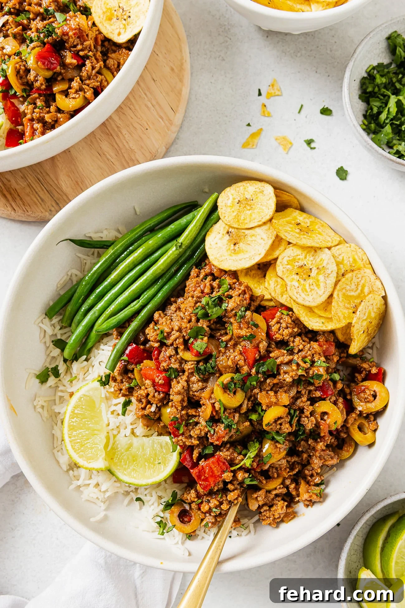 Flavorful Picadillo served over a bed of white rice, accompanied by vibrant green beans and crispy plantain chips.