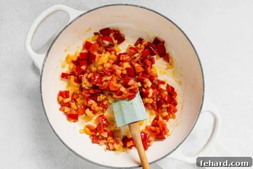 Sautéed onions, bell pepper, and tomato in a white skillet, fragrant and softening for the Picadillo base.