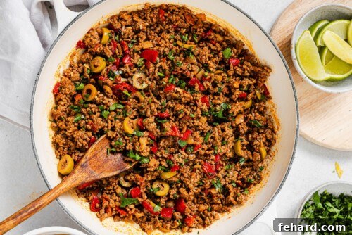 Finished Picadillo in a white skillet, garnished with fresh cilantro, ready to be served as a hearty meal.