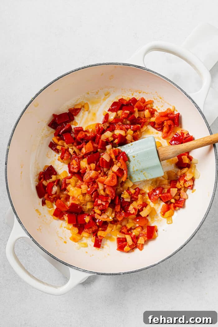 Sautéing diced onions, minced garlic, chopped fresh tomatoes, and vibrant bell peppers in a large skillet with shimmering olive oil.
