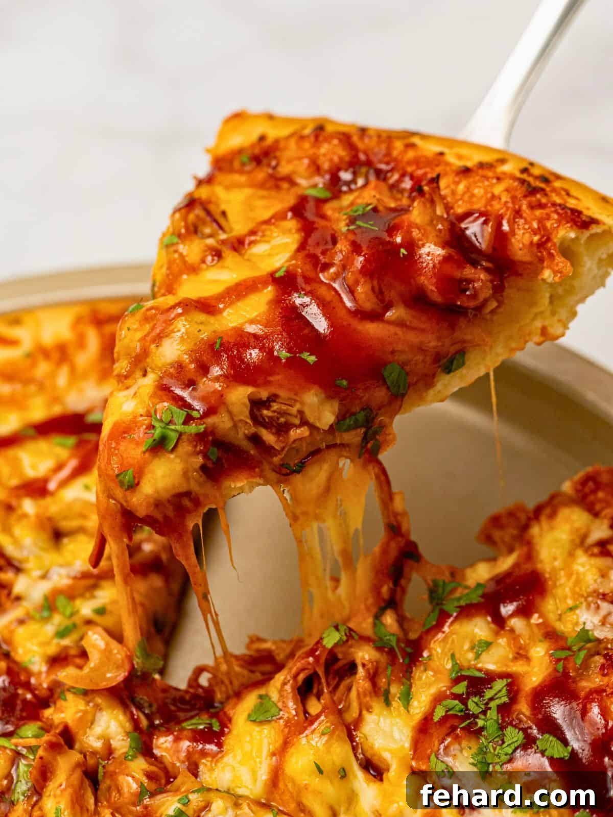 A delicious slice of BBQ chicken pizza being pulled from the pan, showing off a perfect cheese pull and golden crust.