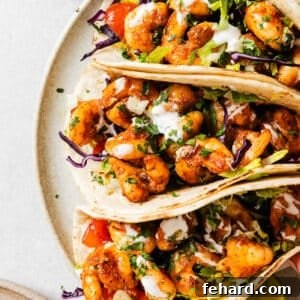 close up of 3 shrimp tacos on a white plate