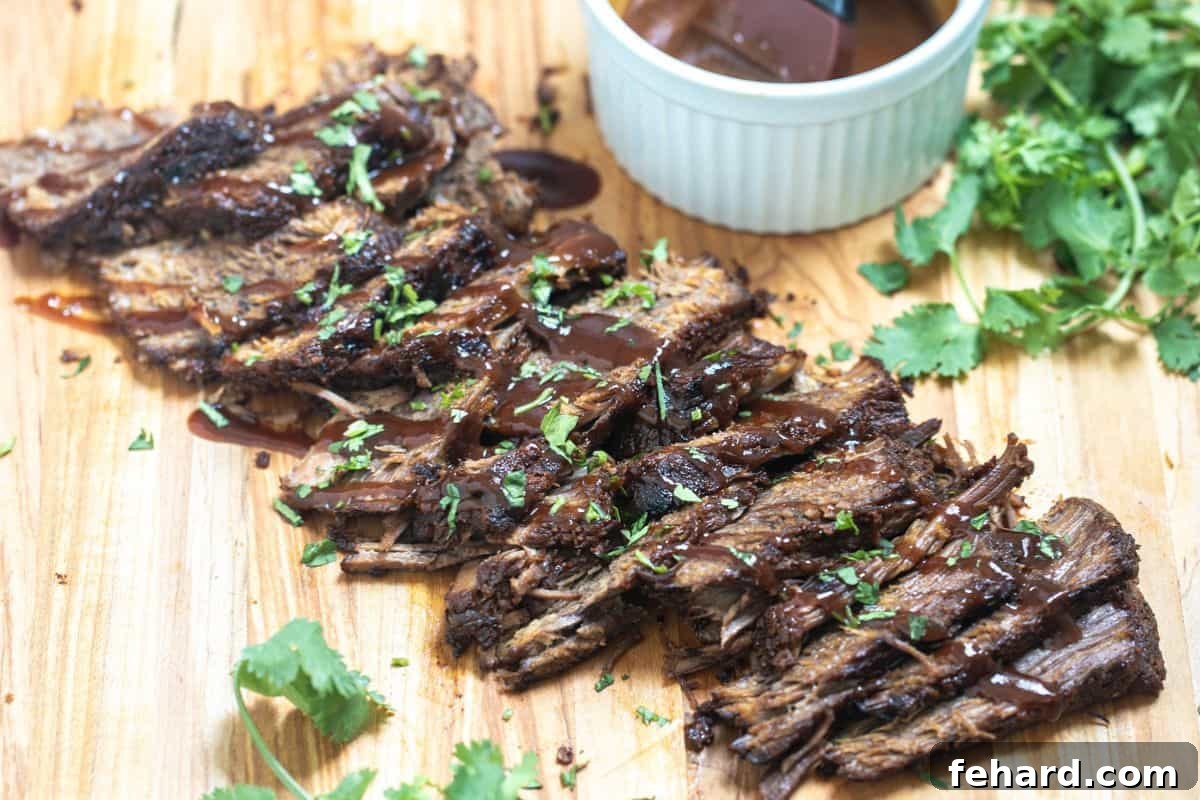 Instant Pot Brisket Sliced Instant Pot Brisket on wooden cutting board drizzled with BBQ sauce and parsley on the side.