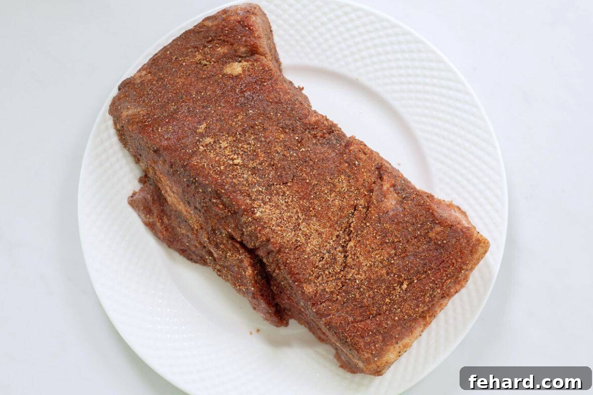 Pressure Cooker BBQ Brisket Beef brisket on white plate covered with sweet and savory spice rub.