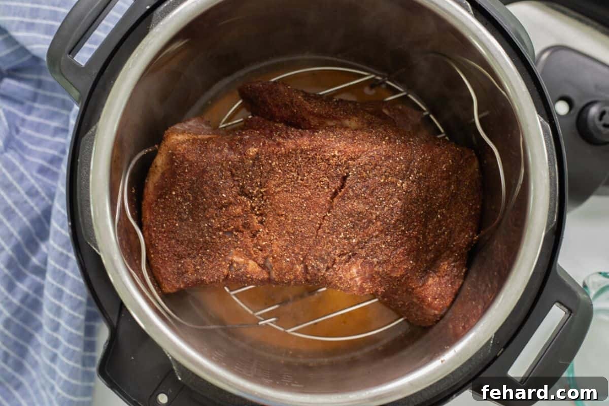 Pressure Cooker Brisket Spice rubbed brisket on metal trivet over apple juice inside Instant Pot.
