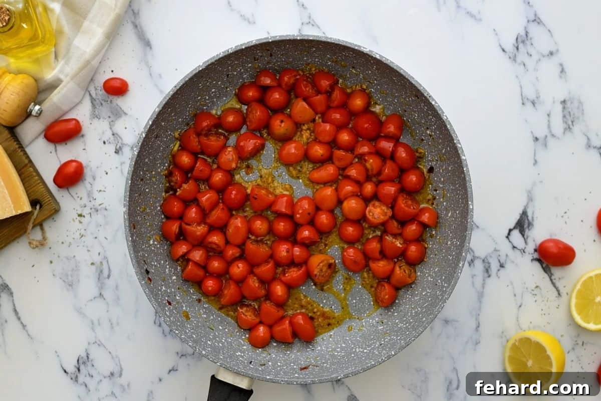 White Bean Pasta with Tomatoes Searing Halved grape tomatoes searing in a sauté pan with seasonings, beginning to blister for the white bean pasta sauce.