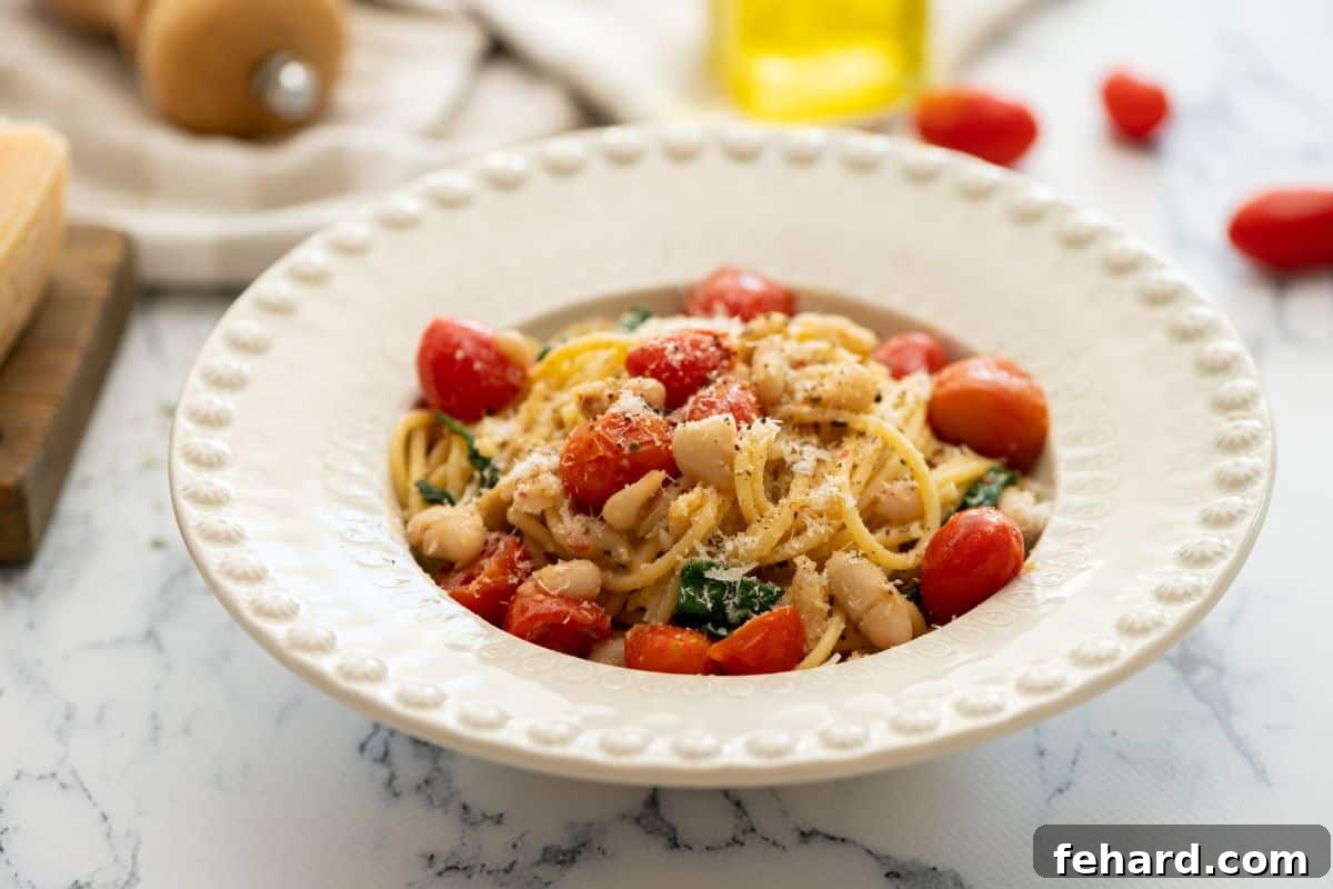 White Bean Pasta Recipe Served A bowl of creamy white bean pasta, garnished with fresh herbs and a generous sprinkle of Parmesan cheese, ready to be enjoyed.
