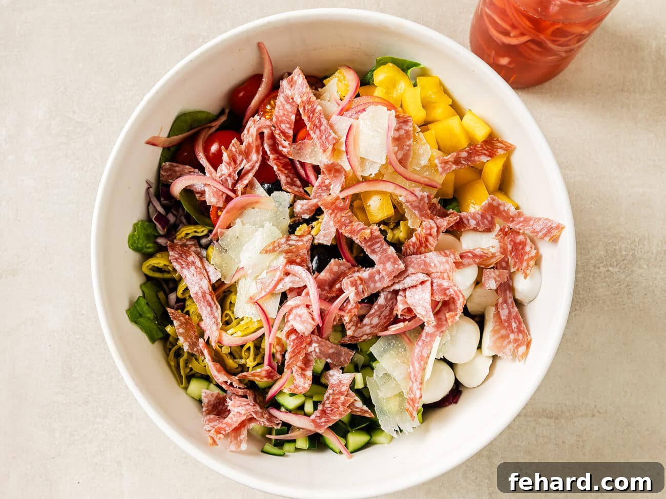 Vibrant Italian Chopped Salad 6 Thinly sliced salami and vibrant pickled red onions are scattered across the top of the already assembled Italian chopped salad ingredients, adding final savory and tangy notes.