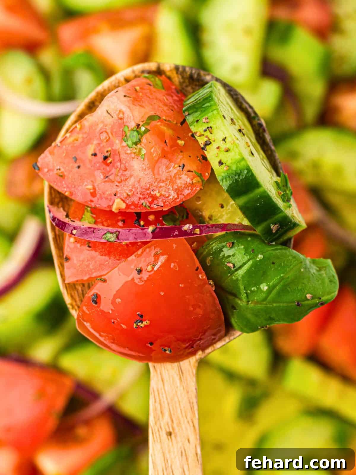 A wooden spoon gently scooping a generous portion of the freshly prepared cucumber tomato salad from a large white serving bowl, showcasing the vibrant colors and appealing texture of the salad. This image conveys the readiness and deliciousness of the dish.