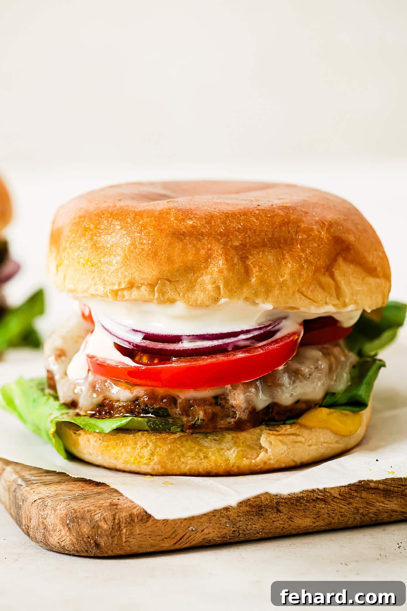 Healthy and Hearty Turkey Burger 2 A close-up of a ground turkey burger on a piece of parchment paper over a cutting board.