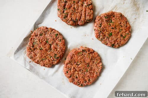 raw burger patties on a baking sheet