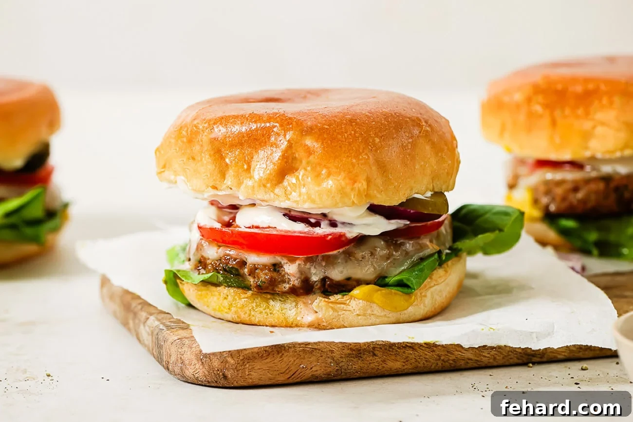 Healthy and Hearty Turkey Burger 9 A side view of three ground turkey burgers with toppings and cheese.