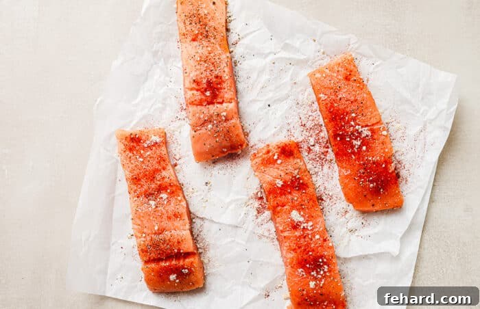 Overhead view of raw, seasoned salmon fillets resting on a paper towel on the kitchen countertop.