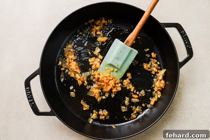 Sautéed onions in a cast-iron skillet, creating an aromatic base for the sauce.