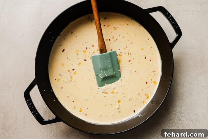 Creamy Marry Me sauce simmering in a cast-iron skillet, enriched with Parmesan and chili flakes.