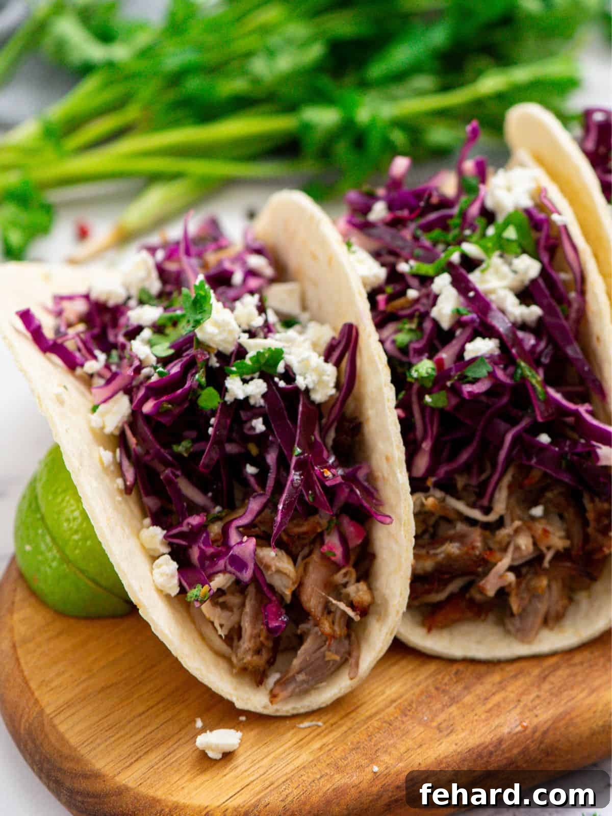 A vibrant tortilla filled with perfectly cooked slow cooker carnitas, generously topped with a fresh Mexican slaw and crumbled queso fresco. The focus highlights the golden-brown crispy edges of the pork and the colorful, fresh toppings.