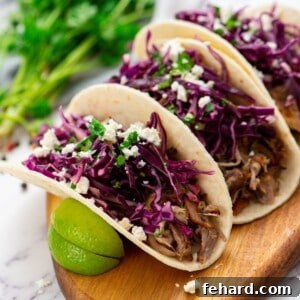 Tortilla filled with slow cooker carnitas and topped with Mexican slaw and queso freso.