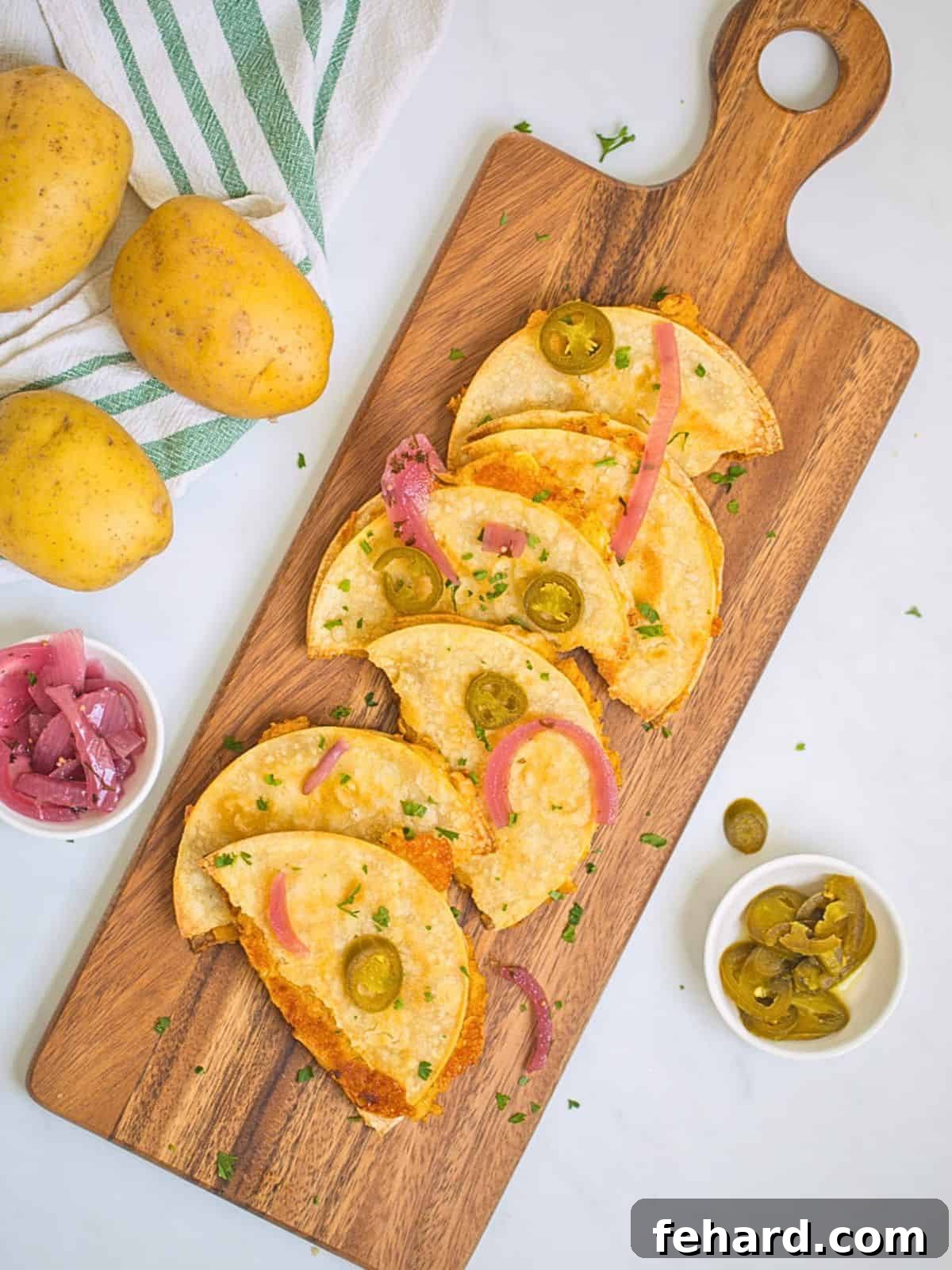 Potato Taco Recipe Crispy potato tacos on wooden cutting board topped with vibrant pickled red onions and spicy pickled jalapenos.