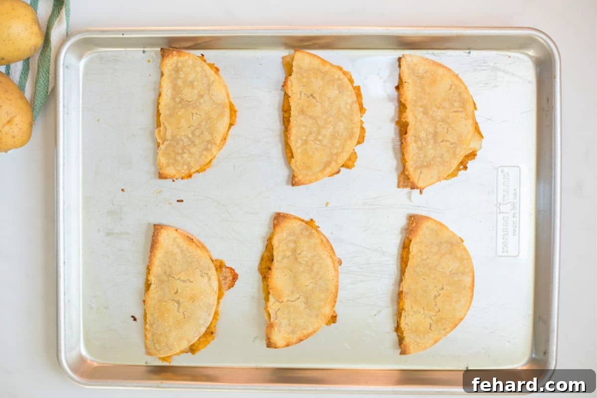Baked Tacos de Papa 6 potato tacos on baking sheet after being baked.