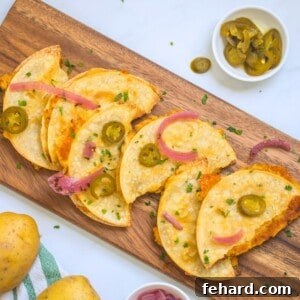 Crispy potato tacos on wooden cutting board topped with pickled red onions and pickled jalapenos.