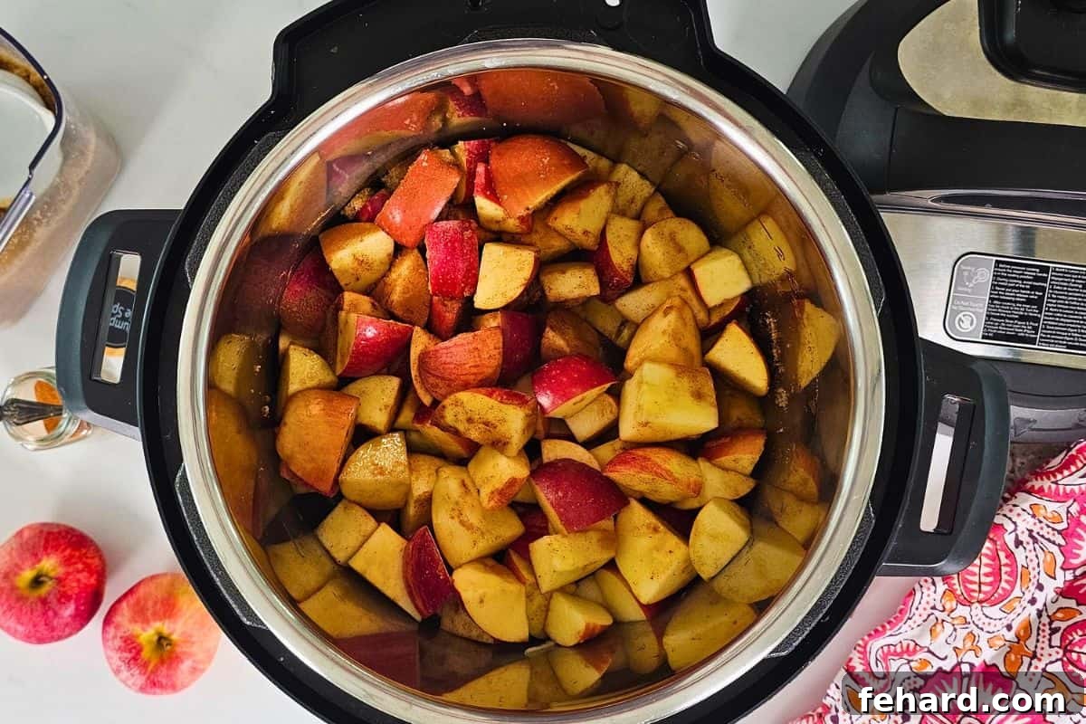 Pressure Cooker Apple Butter Diced apples with brown sugar, spices, and cinnamon inside the inner pot of a pressure cooker, ready for cooking.