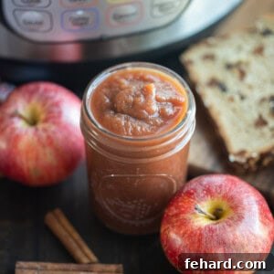 Jar of Instant Pot Apple Butter next to an Instant Pot, fresh apples, and pressure cooker.