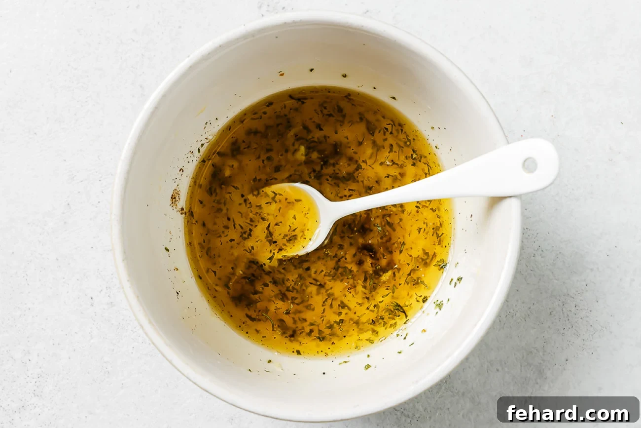 Lemon, garlic, olive oil, and dried herbs in a white bowl.