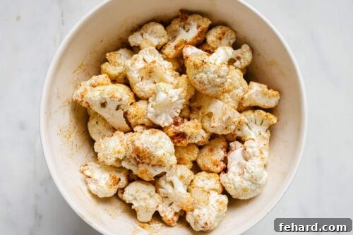 Seasoned raw cauliflower florets in a bowl.