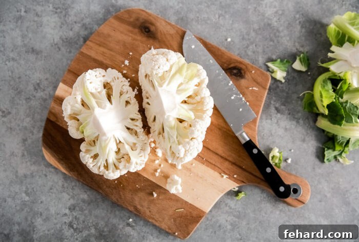 Cauliflower head cut in half on a wooden board.