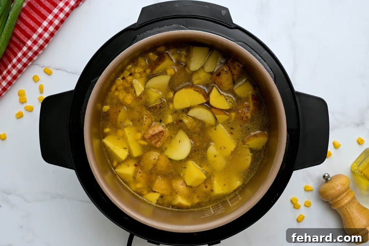 Potatoes and Corn Ready for Pressure Cooking Diced Yukon gold potatoes, fresh corn kernels, and vegetable broth are combined in the Instant Pot's inner pot, ready for pressure cooking to create the potato corn chowder.