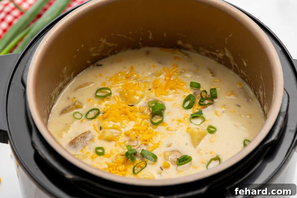 Serving Instant Pot Potato Corn Chowder A close-up of a hearty Instant Pot Potato Corn Chowder in the inner pot, beautifully topped with vibrant sliced green onions and melted shredded cheddar cheese, ready to be served.